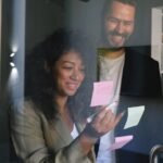 Diverse happy business partners checking stickers on glass door and smiling together in office